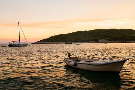 海上航行摄影照片_在热带岛屿上日落时，小船和游艇停泊在海上