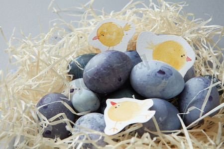 手绘环保摄影照片_彩色鸡蛋在马槽由木材和手工画鸡，特写。手绘复活节彩蛋