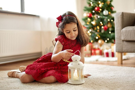 圣诞节，假期和童年的概念—快乐的小女孩玩灯笼在家里。小女孩与灯笼在家里圣诞节