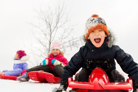 童年，雪橇和季节概念—一群快乐的小孩子在冬天滑雪橇。快乐的孩子在冬天滑雪橇