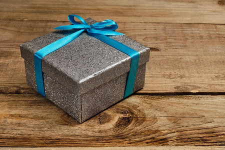 银蓝摄影照片_礼物生日圣诞节礼物概念—银礼品盒与蓝色丝带在老木背景蓝丝带礼盒