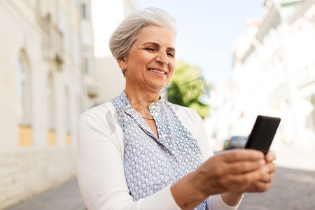 技术，老年和人的概念—快乐的高级妇女与智能手机在夏天。快乐的高级妇女与智能手机在夏天