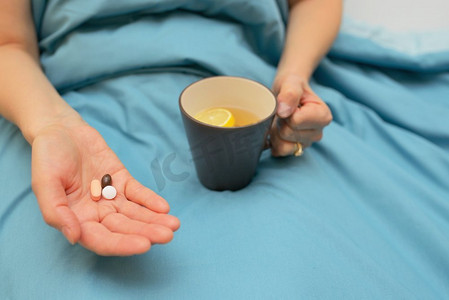 柠檬手摄影照片_妇女的手服用药物在床上