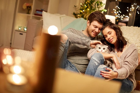天猫天猫圣诞摄影照片_宠物，hygge和人的概念—快乐的夫妇与猫在家里。快乐的夫妇与猫在家里