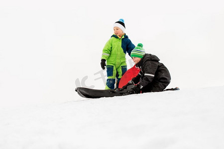 童年，雪橇和季节概念—小孩子在冬天滑下雪山。冬天，孩子们在雪橇上滑下雪山