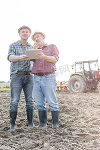 农民顶着天空在农场讨论数字平板电脑