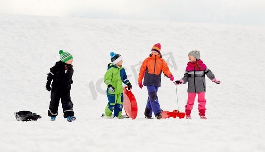 童年，雪橇和季节概念—一群快乐的小孩子在冬天户外雪橇。快乐的小孩子与雪橇在冬天