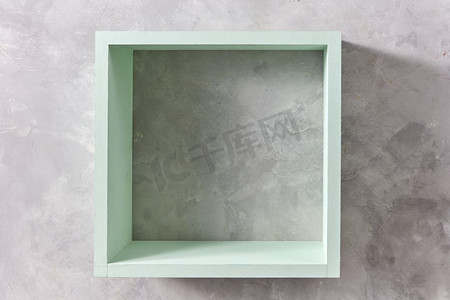 正方形木盒子摄影照片_方形绿色木墙与灰色混凝土墙隔离，并留有复制空间。产品展示模板。隔绝在石灰色背景上的盒子架子。