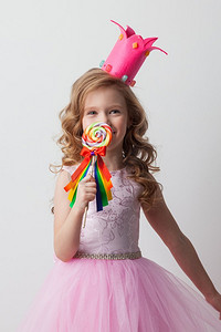 美丽的小糖果公主女孩在冠拿着大棒棒糖和微笑。糖果公主女孩与棒棒糖