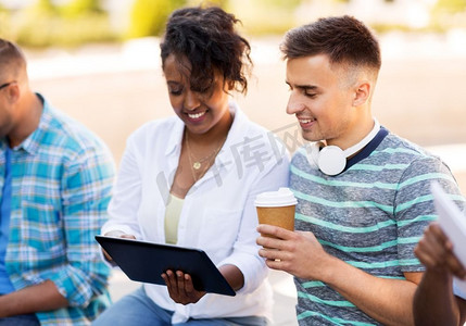 科技与人的概念-一群快乐的朋友，在户外玩平板电脑和喝咖啡。在户外享受平板电脑和咖啡的快乐朋友