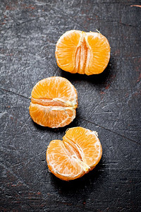 去皮的橘子。在黑暗的背景下。高质量的照片。去皮的橘子。在黑暗的背景下。