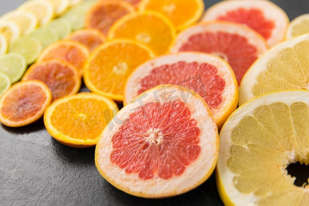 牛肉排酸摄影照片_食物和健康饮食理念-葡萄柚、橙子、柚子、柠檬和酸橙片的特写。不同柑橘果片的特写
