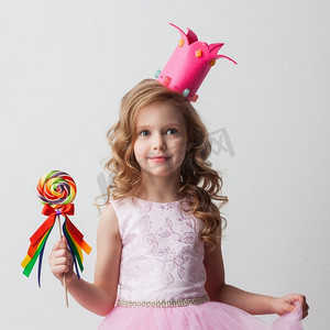 艾莎公主摄影照片_美丽的小糖果公主女孩在冠拿着大棒棒糖和微笑。糖果公主女孩与棒棒糖