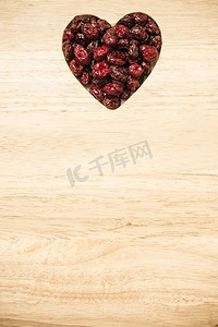 健康高纤维食品，有机营养。干的蔓越莓蔓越莓果实在心的形状在木表面背景