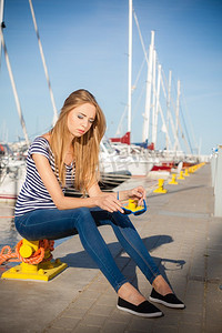 旅游旅游与人的观念。戴着蓝色心形太阳镜的时尚金发女孩在码头与港口的游艇对峙