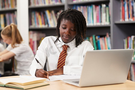女高中生穿着制服在笔记本电脑工作在图书馆