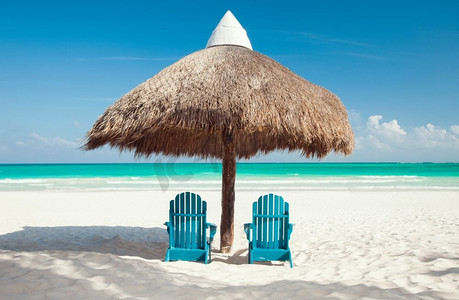 浪漫海岛旅行摄影照片_浪漫度假概念-热带海滩，帕拉帕下面有两把太阳椅。热带海滩Palapa下的两把太阳椅