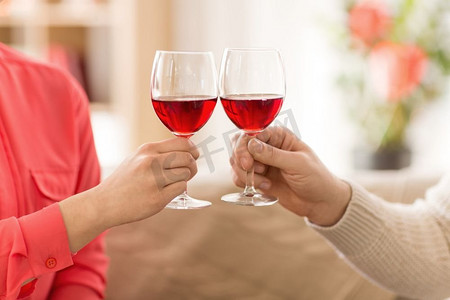 庆祝，饮料和酒精概念—夫妇的手叮当红葡萄酒杯。手的夫妇与红葡萄酒杯祝酒 