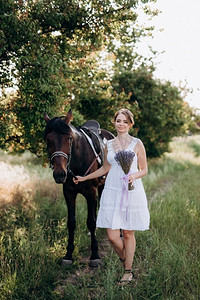 一个女孩在一个白色太阳裙散步与棕色的马在村庄
