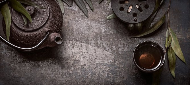 文案背景摄影照片_传统的亚洲绿茶套装，茶壶、茶杯和蜡烛，背景为深色质朴，带有文案空间、横幅或模板，俯视