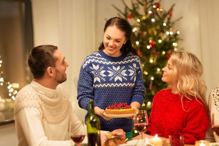 节日和庆祝概念-快乐的朋友在家里吃圣诞晚餐。快乐的朋友们在家里吃圣诞晚餐