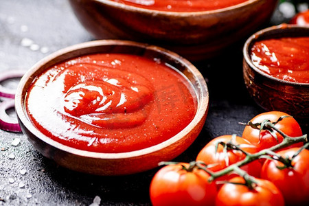 木盘子里的番茄酱。黑色背景。高质量的照片。木盘子里的番茄酱。 