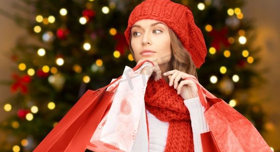 人、假日和销售概念—有购物袋的妇女在圣诞树光背景妇女与购物袋超过圣诞灯