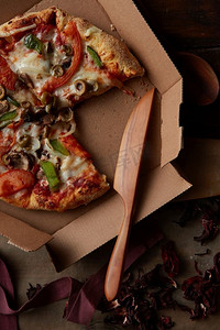 美味的意大利披萨配蔬菜和纸板快递箱，平放。纸板披萨盒里的披萨
