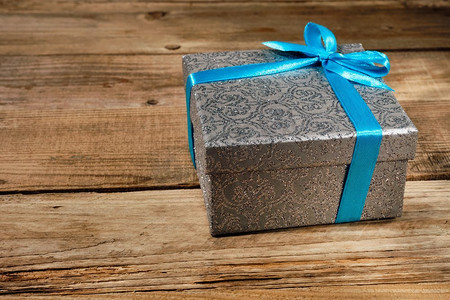 礼物生日圣诞节礼物概念—银礼品盒与蓝色丝带在老木背景蓝丝带礼盒
