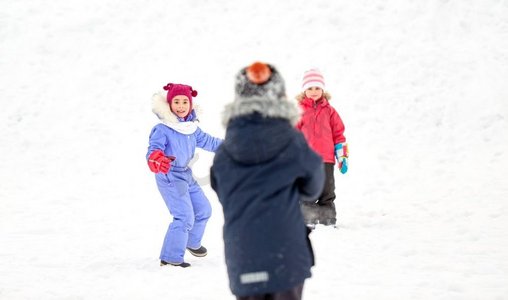 下雪玩耍摄影照片_童年、休闲和季节概念-一群穿着冬装的快乐小朋友在户外玩耍。冬天快乐的小孩子们在户外玩耍