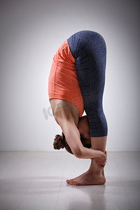 美丽的运动健身瑜伽女练习瑜伽体位Uttanasana—站立向前弯曲姿势。Woman practices yoga asana Uttanasana