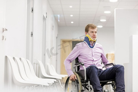 年轻人在医院走廊坐在轮椅上的颈托