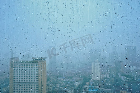 雨点摄影照片_雨水滴在窗口玻璃纹理与摩天大楼在背景。雨点落在窗户上