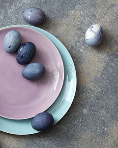 粉蓝摄影照片_粉色和蓝色的盘子，复活节彩蛋，手工制作的机器人混凝土，背景平放。粉蓝相间的复活节彩蛋盘子