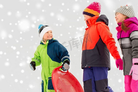 童年，雪橇和季节概念—一群快乐的小孩子在冬天雪橇。快乐的小孩子与雪橇在冬天