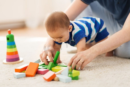 家庭，父亲和人的概念—亚洲男婴和父亲玩玩具块在家里。男孩和父亲在家里玩玩具