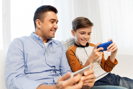 休闲、科技、家庭和人的概念-家里有智能手机，幸福的父子。家中有智能手机的幸福父子