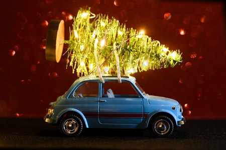 提供圣诞节或新年的蓝色复古玩具车在红色节日背景照明的树汽车送圣诞树或新年树