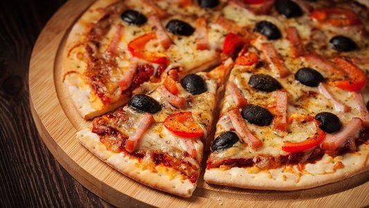 信箱全景图，餐桌上的木板上有切片的火腿披萨和辣椒和橄榄。火腿披萨关闭信箱