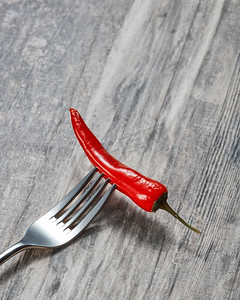 红色叉摄影照片_新鲜的红辣椒在金属叉在木灰色背景与复制空间。红色热辣椒在一个金属叉在木背景