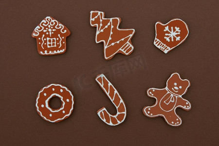 圣诞屋圣诞摄影照片_自制姜饼饼干与不同的形状孤立在一个棕色背景。圣诞背景圣诞自制姜饼屋饼干