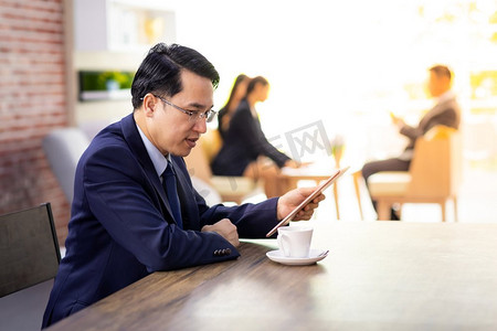 商人的画象在咖啡馆工作有智能电话和平板电脑与企业团队在背景使用的合作背景工作