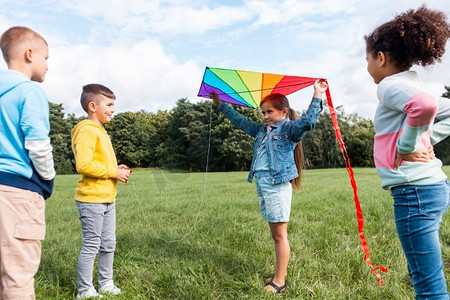 童年，休闲和人的概念—一群快乐的孩子在公园玩风筝。快乐的孩子与风筝玩在公园