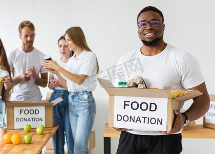 食物捐赠摄影照片_微笑的男性志愿者拿着食物捐赠