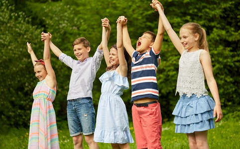 童年和友谊的概念--快乐的小朋友在夏令营里手牵手。快乐的孩子们在夏季公园里举起手