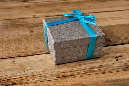 礼物生日圣诞节礼物概念—银礼品盒与蓝色丝带在老木背景蓝丝带礼盒