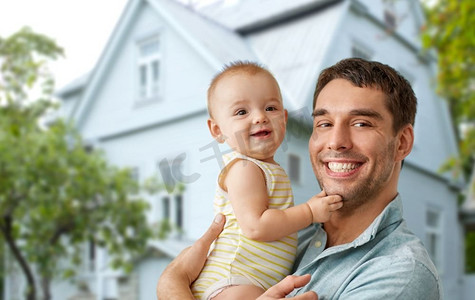 家庭，家和房地产概念—快乐的父亲抱着小宝贝女儿在房子背景。快乐的父亲抱着宝贝女儿在房子