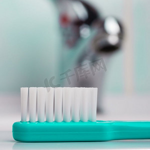 牙齿保健的健康概念。特写镜头绿色刷牙刷在浴室在水槽，水龙头在背景