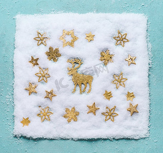 雪地里的圣诞驯鹿，浅蓝色背景上有金色的雪花，俯视。平躺着。冬季作文与度假理念