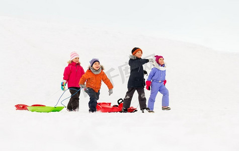 童年，雪橇和季节概念—一群快乐的小孩子在冬天雪橇。快乐的小孩子与雪橇在冬天